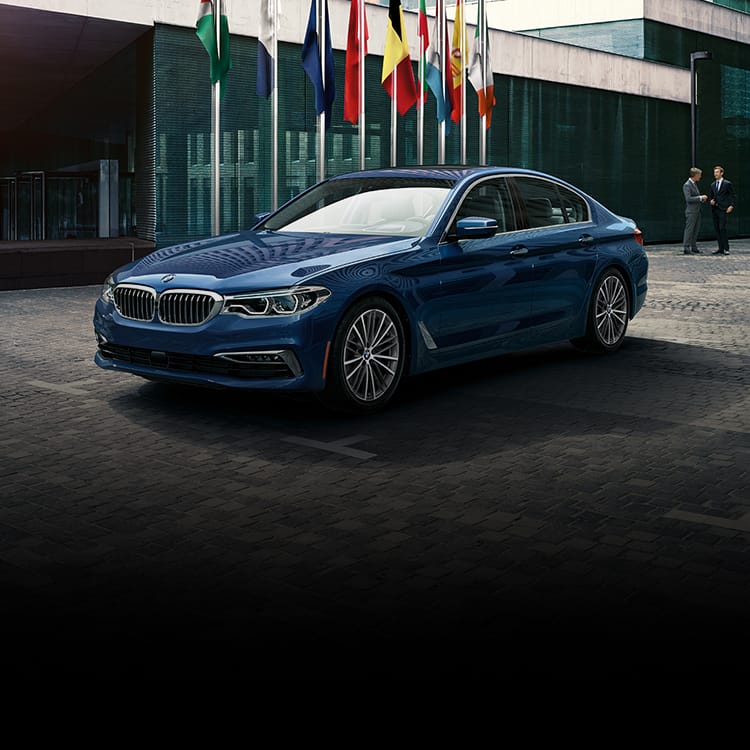 A BMW 5 Series Sedan parked outside an embassy building