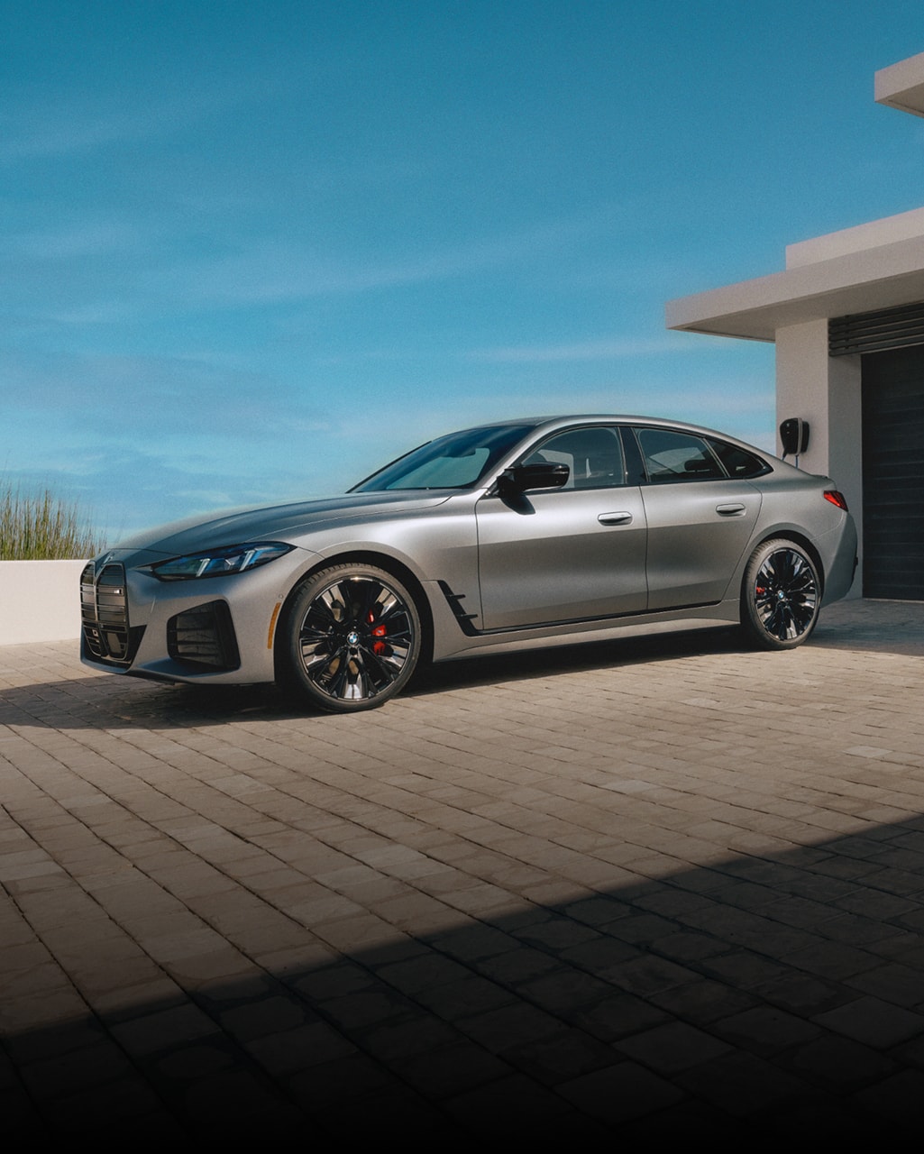 The BMW i4 M50 on a brick paved driveway of a modern home