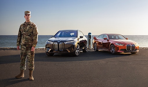 A US military member in front of 2 BMW Evs