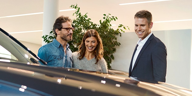 An excited couple chats with a BMW dealer