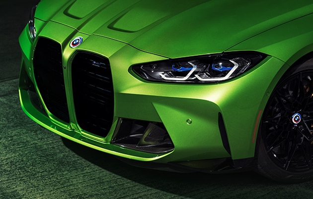 Front detail of BMW M4 in Java Green Metallic, showcasing the BMW 50 Years Emblem