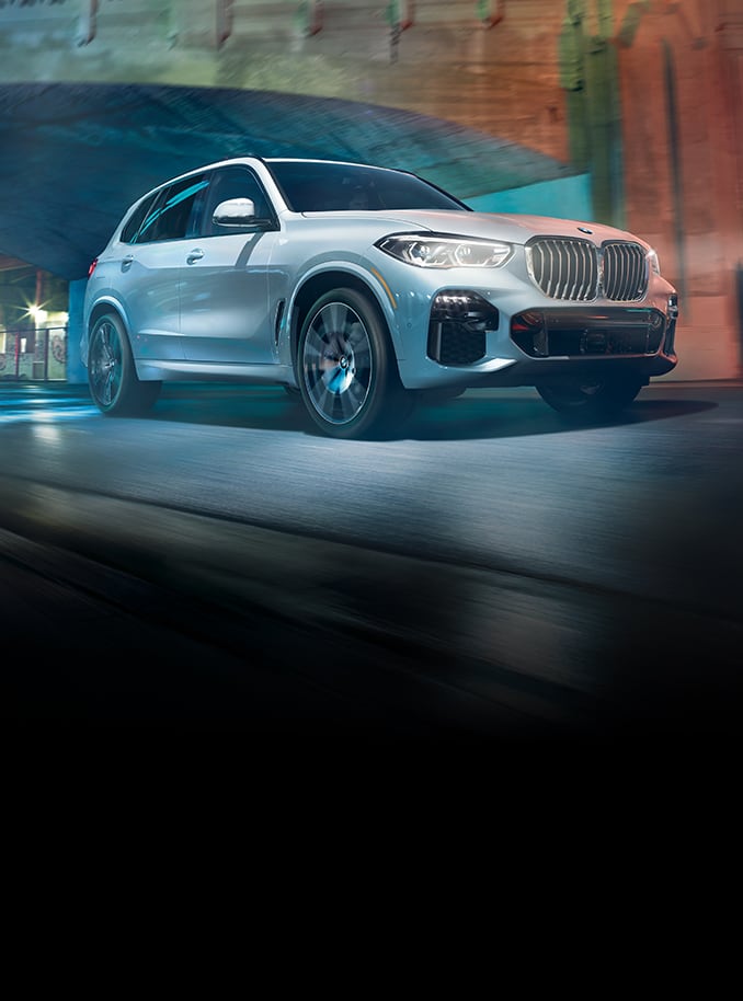 BMW X5 in Mineral White Metallic emerging from a bridge in the city