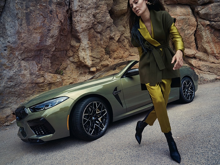 A stylish, confident female driver walks away from the 2025 BMW M8 Competition Convertible