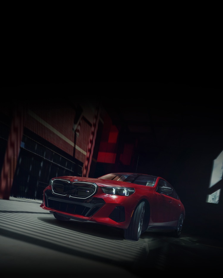 Angled front-to-side view of the BMW i5 M60 emerging from the shadows