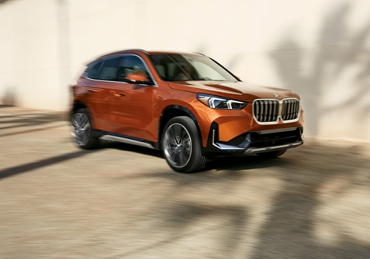 Side angled view of the BMW X1 SUV driving with blurred background