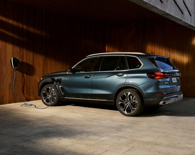 The BMW X5 xDrive50e Plug-in Hybrid charges at a home charging station