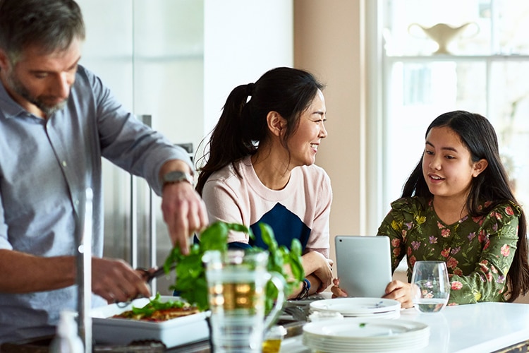 A family prepares dinner while conversing with a BMW representative on their tablet